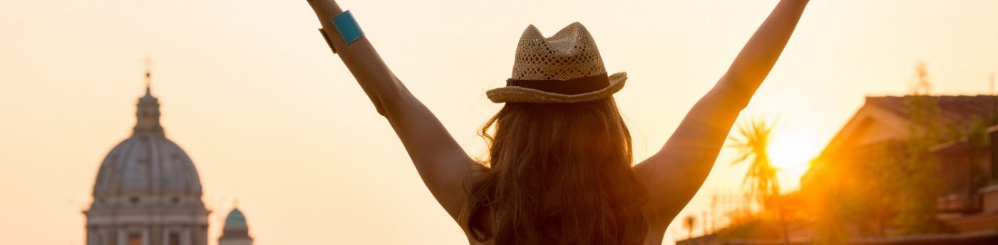 Woman from behind with outstretched arms in Rome at sunset