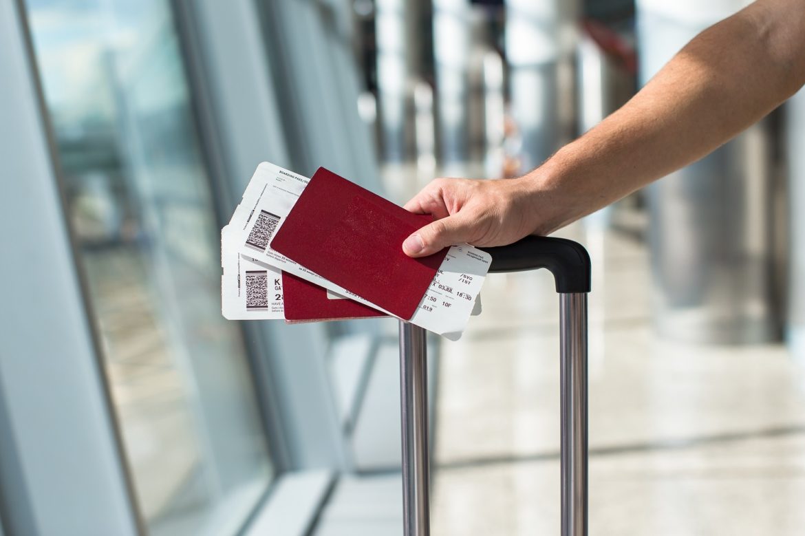 Closeup of man holding passports and boarding pass at airport man passport luggage