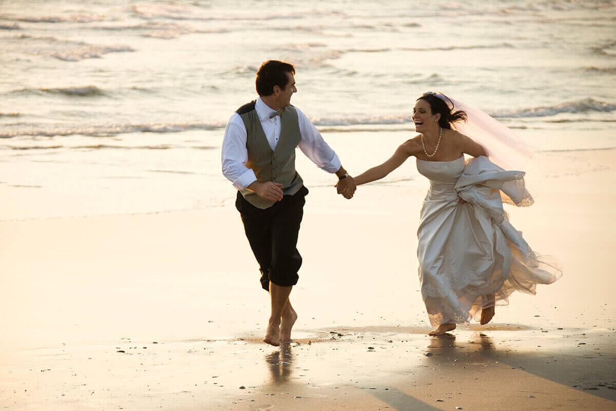 bride and groom running on beach